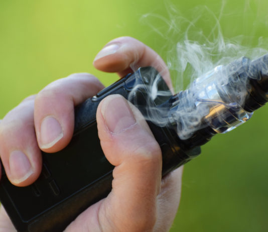 Vapor product curriculum in schools required by House bill vape HB 287: Hand holding an e-cigarette surrounded by swirling smoke.