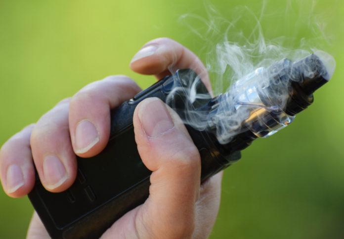 vape HB 287: Hand holding an e-cigarette surrounded by swirling smoke.
