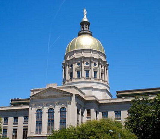 Safety and security at the Georgia Legislature Georgia's gold dome Capitol building in Atlanta. surrounded by grren trees against a cloudless, bright blue sky.