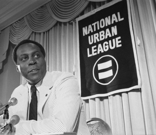Vernon Jordan, activist, former Clinton adviser, has died Vernon Jones at press conference in 1977: a Black man wearing white seersucker suit and dark tie standing at podium speaking into microphones