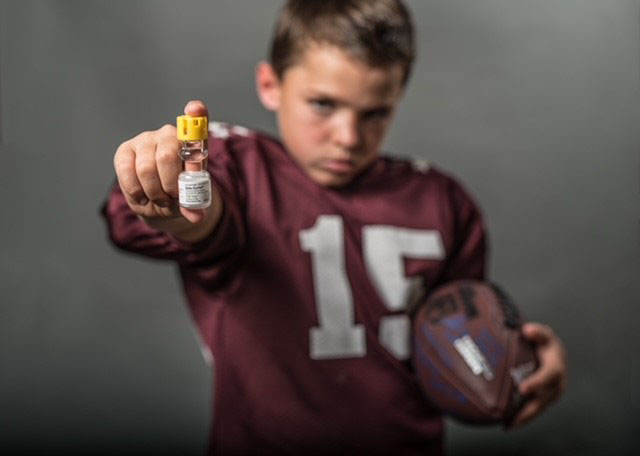 Jarom Bill: Little boy in burgandy football jersey #15 holding glass vial with yellow cap of Solu-Cortef