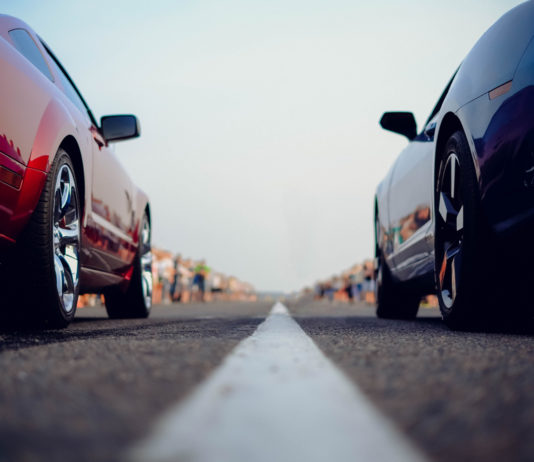 Debate on election bills, Right to Visit Act progress and drag racing bill Drag racing: Closeup of one red and one blue car at starting line on city street with out-of-focus spectators lining the street in background
