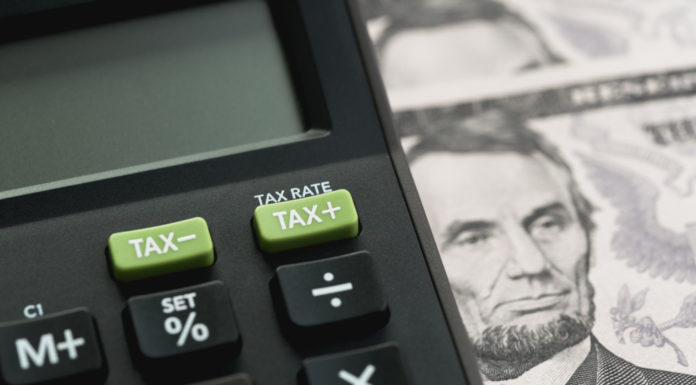 Georgia Senate sends $140M state income tax cut to Kemp Closeup of black calcuator with lime green tax keys beside a five dollar bill