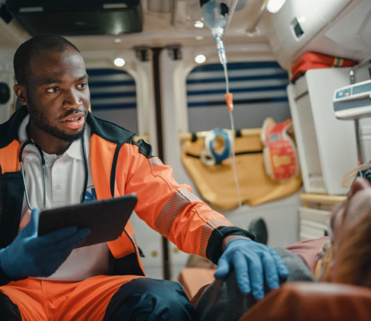 Georgia lawmaker aims to address drastic increase in opioid deaths Paramedic wearing neon orange uniform and blue gloves talking to patient in ambulance
