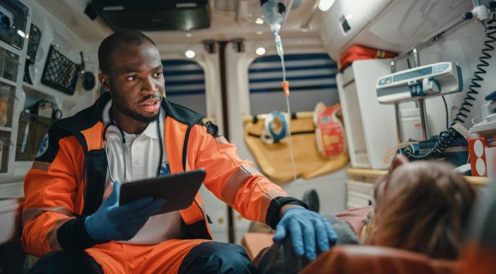 Georgia lawmaker aims to address drastic increase in opioid deaths Paramedic wearing neon orange uniform and blue gloves talking to patient in ambulance