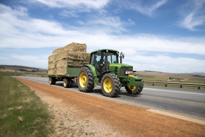 Tractor Right-of-Way Law: Green tractor wit trailler hauling hay bales on public road
