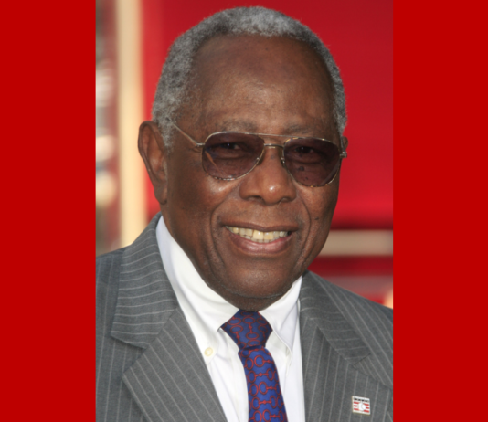 Atlanta school replacing KKK leader’s name with Hank Aaron’s Hank Aaron headshot of smiling, older, gray-haired Black man wearing wire-rim aviator glasses and gray pinstripe suit with white shir and navy tie