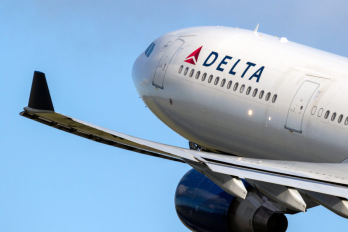 Closeup of Delta airplane taking off in clear blue sky
