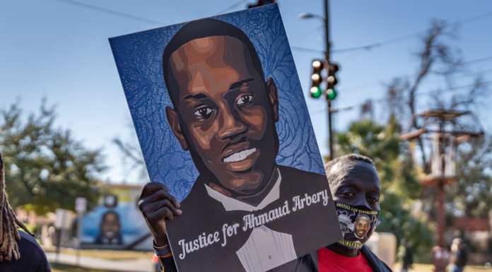 Black man’s death moves Georgia to end citizen’s arrest law Citizen's Arrest Law Ahmaud Arbery: Black man wearing face mask and black jacket holds up sign with picture of Ahmaud Arbery