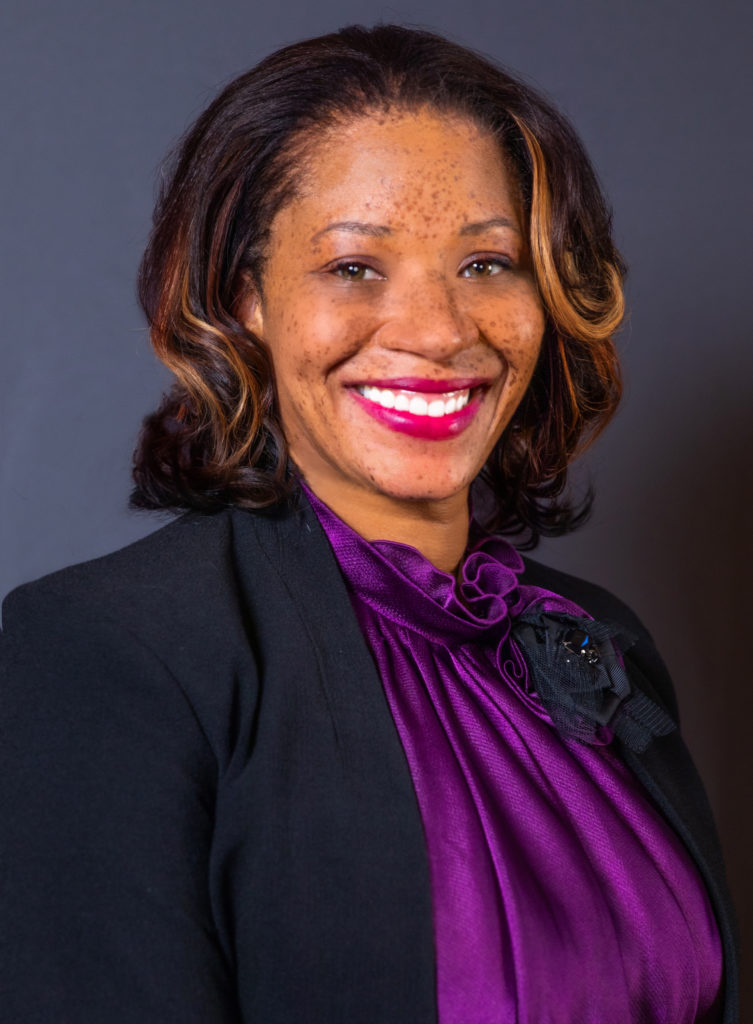 Medicaid expansion: Rep. Mesha Mainor headshot - Black womain with short brown hair wearing ourple suit kacket with lighter purple blouse smiling in front of a navy background