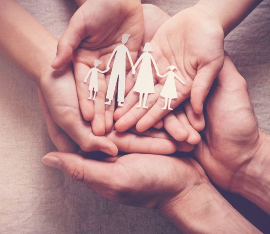 Georgia establishing new therapeutic foster care program Therapeutic foster care: Hands palms up overlapping holding paper cutout of 2 adults with 2 children holding hands