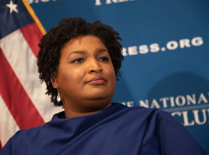 Stacey Abrams in front of US flag giving speech