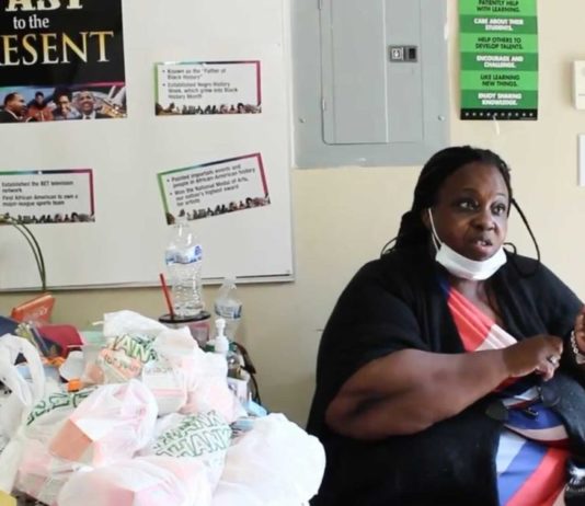 Cobb County residents want legislative change amidst eviction moratorium Black woman sitting at table next to food donations with signs on wall behind her