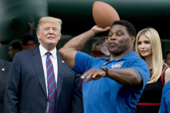 Herschel Walker throwing footbal in front of former President Donald Trump and Ivanka Trump