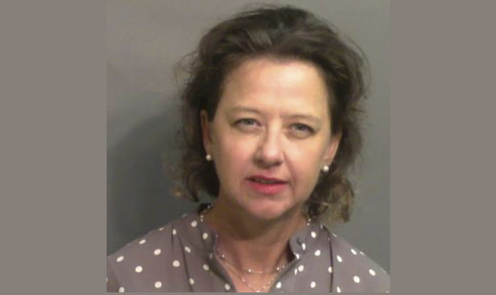 Jackie Johnson mugshot: Woman with short brown hair and earrings wearing a tan top with white polka dots