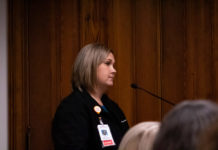 Georgia medical professionals ask for protection as workplace assaults rise white lady with short blond hair in black scrubs on with a nurses badge at a podium with a mic with a brown background