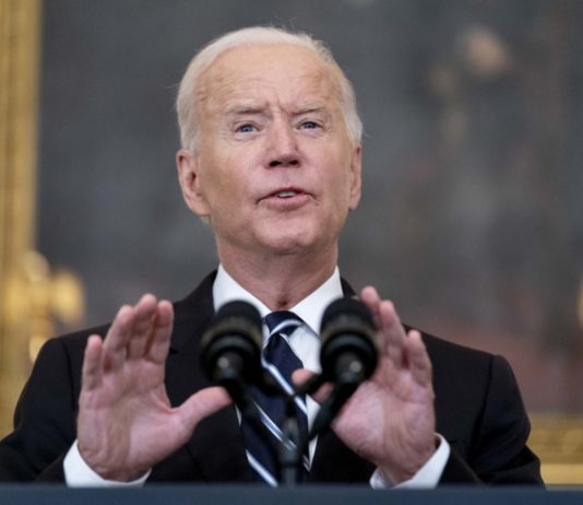 Federal mandate takes vaccine decision off employers’ hands feds mandate vaccine: Pres Biden - older, grey-haired man - speaking into microphone wearing dark suit, white shirt and navy striped tie