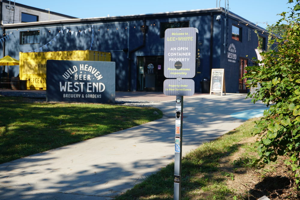 a sign in front of blue building with Wild Haven West End Brewery and Gardens written on it 