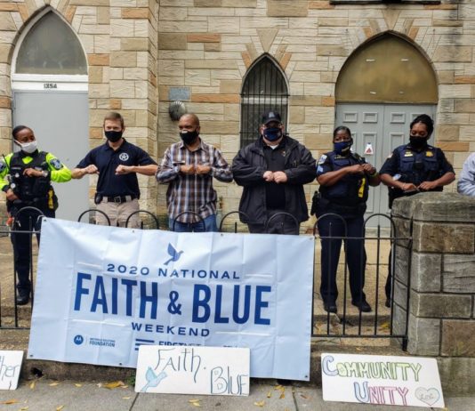 Law enforcement and faith leaders will participate in community outreach weekend seven officers linked up arm to arm in mask in front of a church