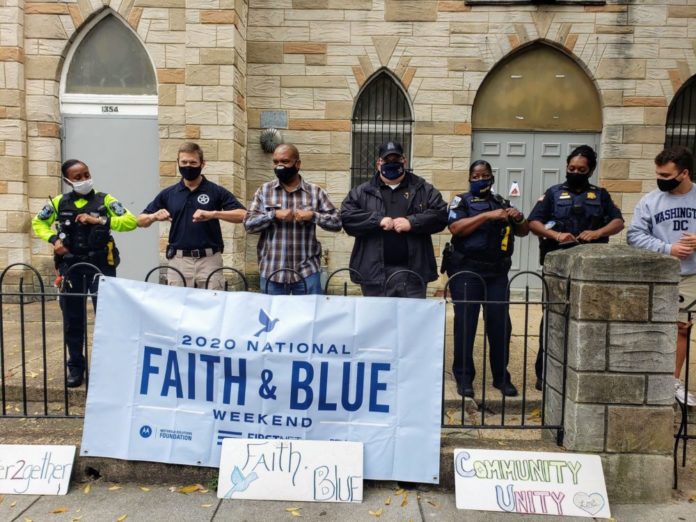 seven officers linked up arm to arm in mask in front of a church