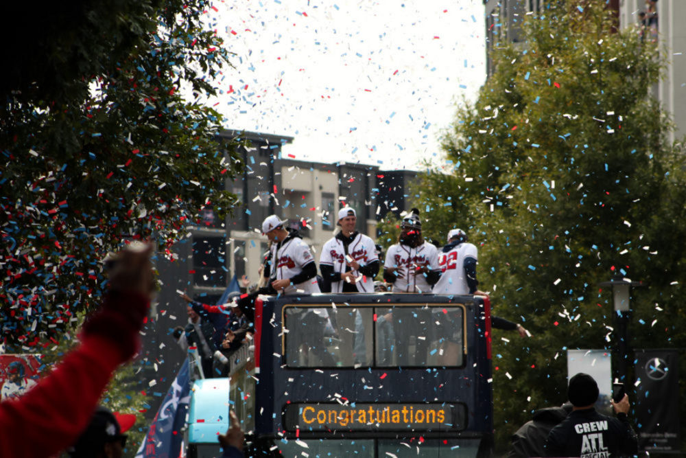 Atlanta Braves parade: four men on a black double decker bus wearing white jerseys with red writing that says Braves