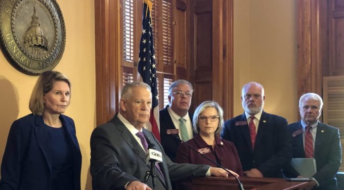 House Speaker holds news conference on Georgia’s redistricting history GA Senate redistricting debate: 4 white men in business attire with 1 white woman with glasses in a burgundy suit standing behind a wooden podium with a American flag and Senate general Assembly seal on the wall