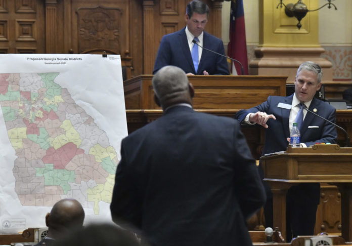 Redistricting Debate: black balld man with navy blue suit looking at a man in a wooden podium