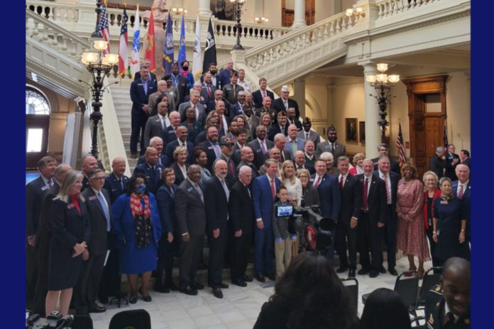 Georgia Capitol Senators honor veterans: Over 80 men and women in business attire on the Georgia Capitol lobby steps facing multiple photographers' cameras seen in foregroundgraphers
