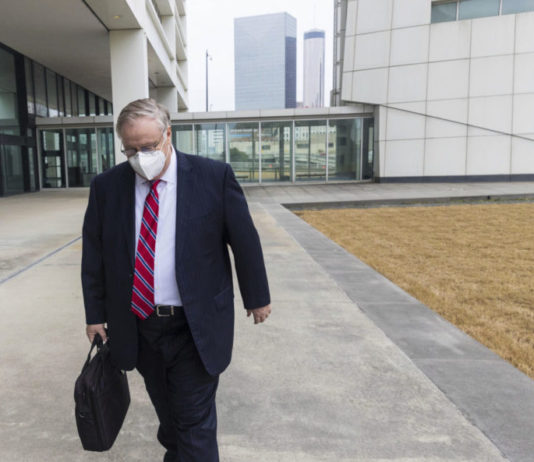 $2.5M theft scheme: Georgia ex-official begins prison term Georgia insurance commisioner: White, gray-haired man walking with head down in mask with with a red tie and black suit on