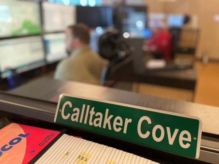 a green sign on an office desk that has Calltaker Cove in white writing on it