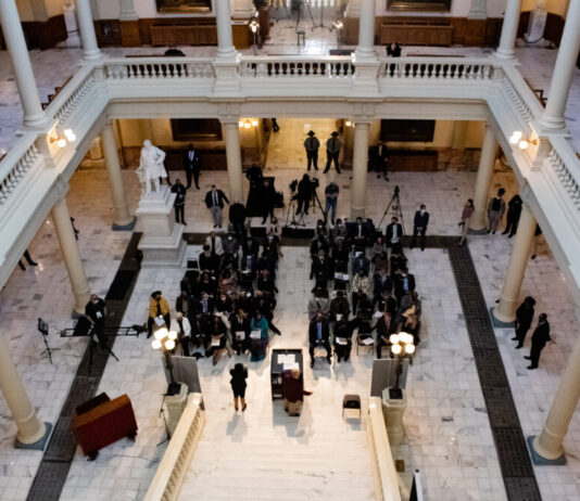 Georgians honor Rev. Martin Luther King Jr. at Capitol overview of lawmakers and Georgia leaders gathering at bottom of Capitol staircase.