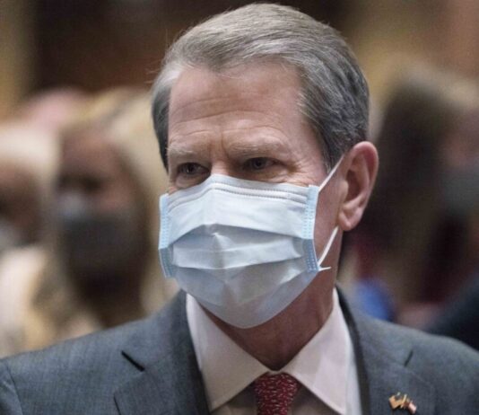 Kemp goes big on spending, seeking $3B increase for Georgia White man in blue face mask and grey suit with red tie