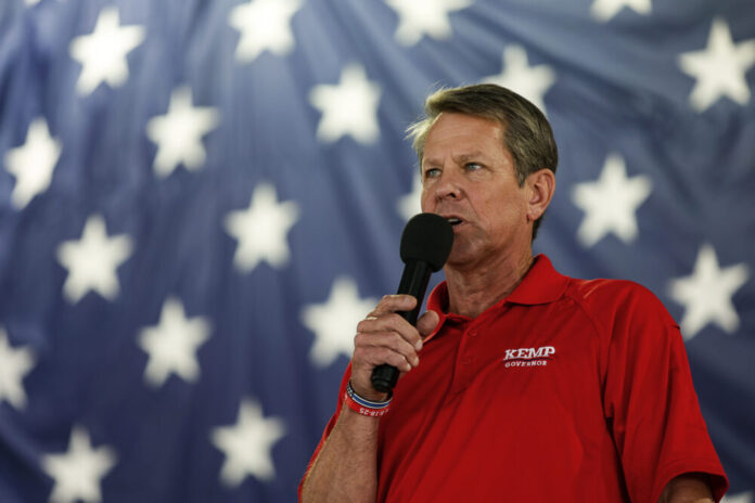 white man holding microphone in red shirt with blue and white star background