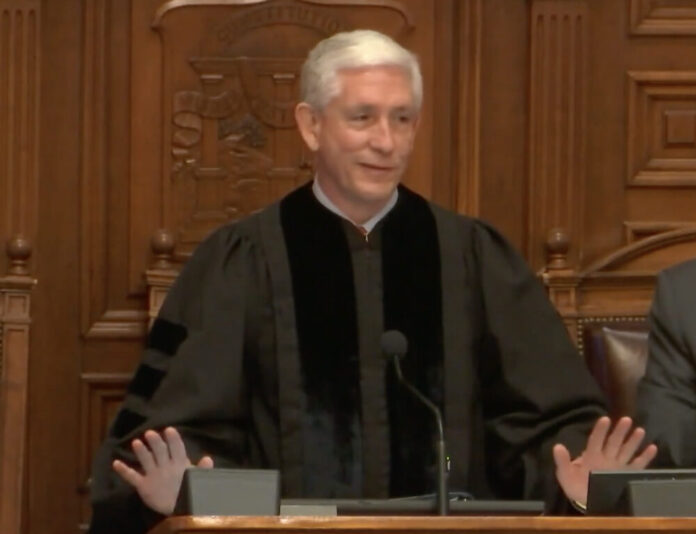 white man in black gown with short white hair.