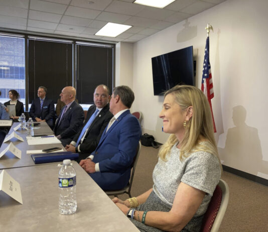 Mandatory sentences make comeback in Georgia anti-crime bill Group of men and women sitting at a table, woman smiling in the front with men talking with eachother