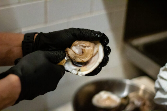inside of an oyster being held by hands in black gloves