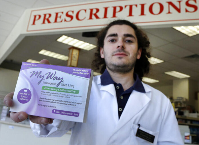 man with dark brown hair holding an emergency contraceptive box.
