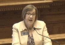 Veterans entering law enforcement could train with free tuition White woman with tan jacket and brown glasses, speaking into microphone