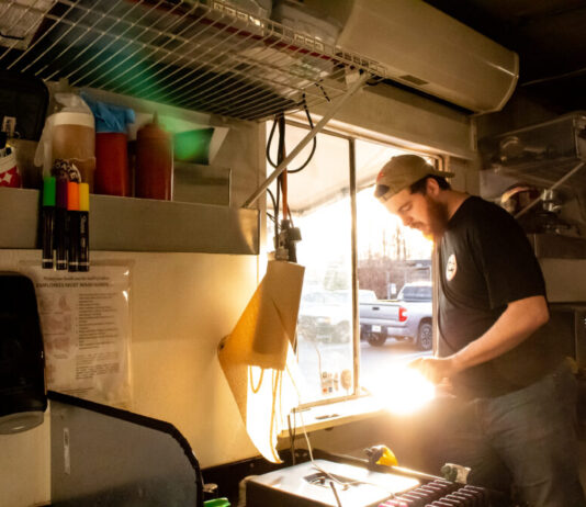 ‘I cried a lot’: Georgia food truck owners worry about high cost of fees and permits man standing near food truck window with grill and food ingredients around