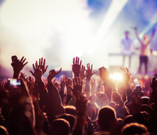 Enhanced protections on the table for Georgia recording artists raised hands from crowd of concert with bright lights and smoke around the stage.