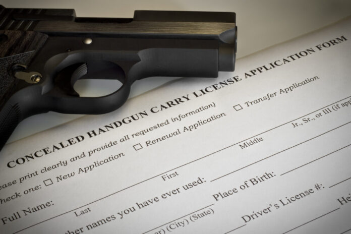 Gun carry license form with black gun laying on top.
