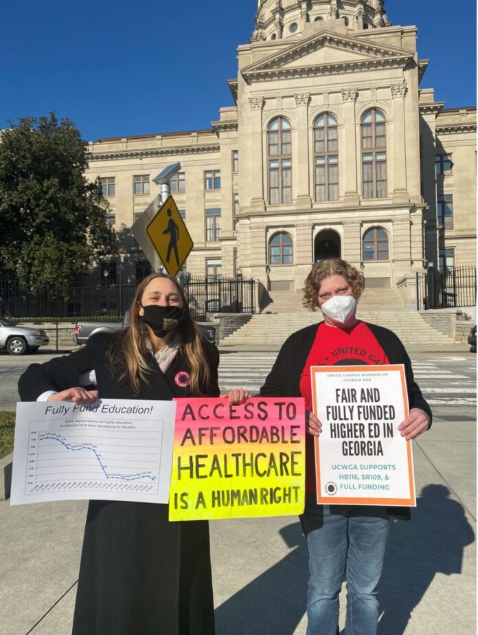Two white women holding signs in front of the Georgia Capital in protest