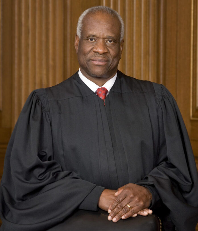 Supreme Court Justice Clarence Thomas -black man with short grey hair with black judge gown and red tie.