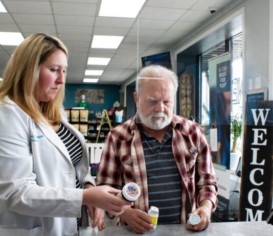 Lawmakers weigh proposal to lower prescription drug costs in Georgia white woman standing on the left, holding pill bottles helping a white man standing to the right