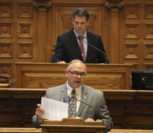 Georgia Senate: Require in-person exams for abortion pills white bald man speaking with glasses on in front of another man standing behind the podium.