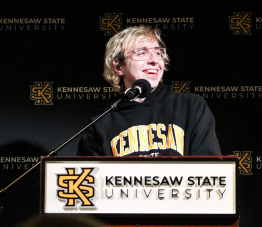 Curiosity and crosswords: Kennesaw State alumnus Raymond Goslow on his “Jeopardy!” journey KSU alumnus Raymond Goslow on his “Jeopardy!”: Blonde, white man speaking at podium with KSU BANNER