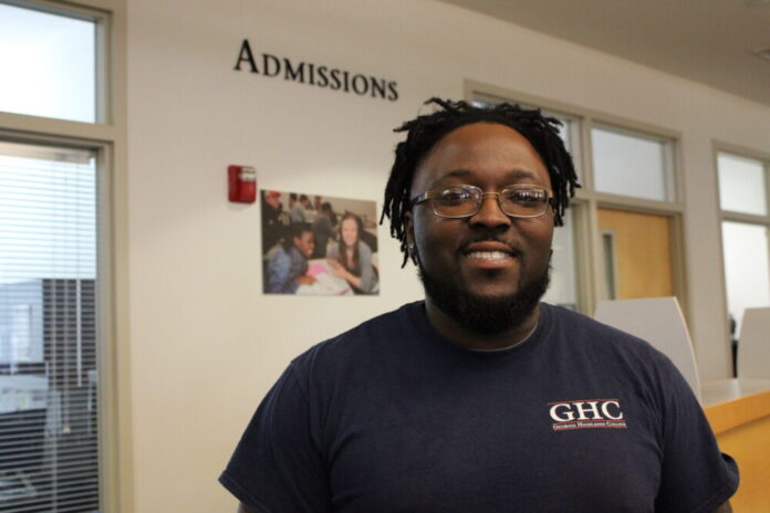 A black man with glasses wearing a GHC shirt