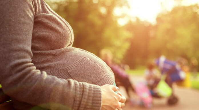 Georgia to require investigations into deaths of pregnant, postpartum women A white pregnant woman sitting on a park bench.