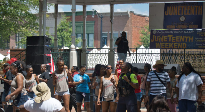 Juneteenth celebration at Marietta Square; group of people dance and celebrate in front of a pavilion on a sunny day