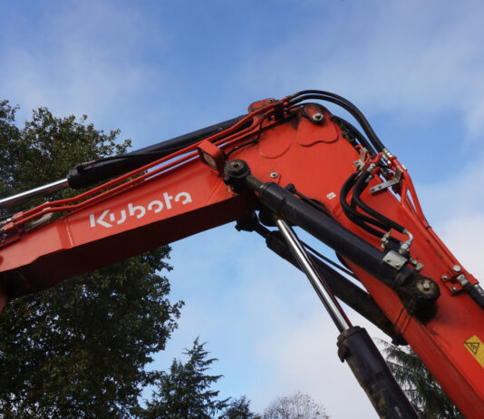 Kubota to invest $140M in new Georgia factory, hiring 500 Georgia, Kubota, Factory: red crane arm with wires in front of green leafy tree with clouds